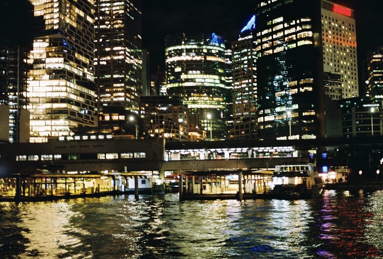 Illuminated skyscrapers reflecting on river at night — photograph by Aleksandar Djeric